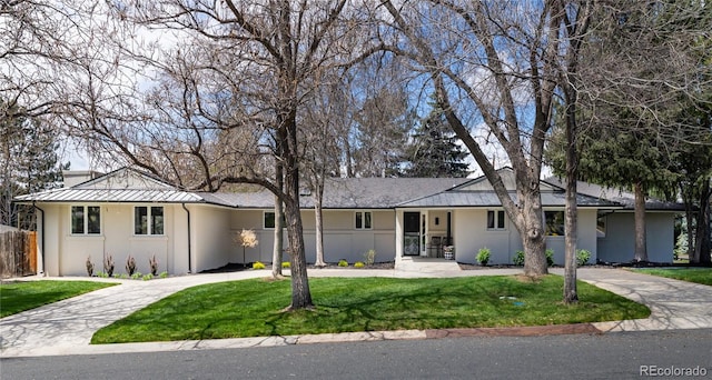 single story home with fence, curved driveway, stucco siding, and a front yard