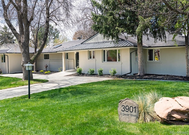 ranch-style house featuring stucco siding, metal roof, a front yard, and a standing seam roof