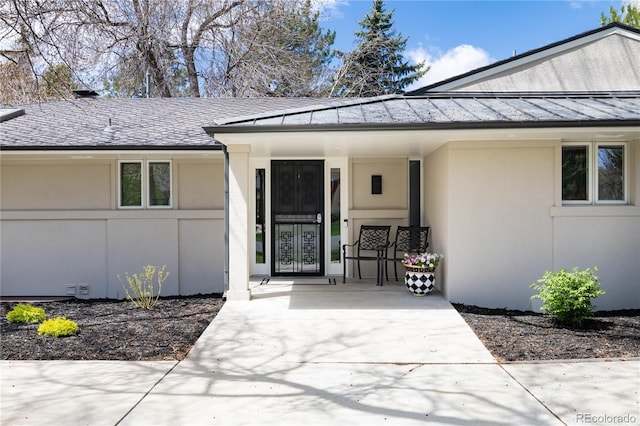 doorway to property with stucco siding, metal roof, and a standing seam roof