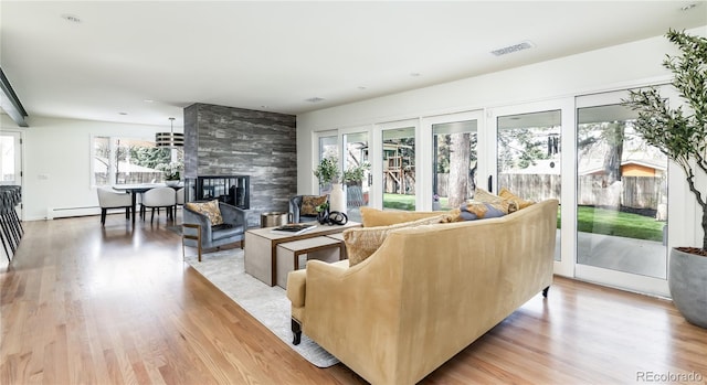 living room with a fireplace, light wood finished floors, and visible vents