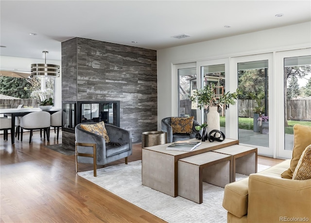 living room featuring a fireplace, visible vents, a healthy amount of sunlight, and wood finished floors