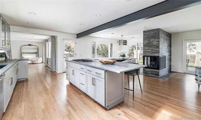 kitchen featuring a kitchen island, a breakfast bar, open floor plan, light wood-type flooring, and a tile fireplace