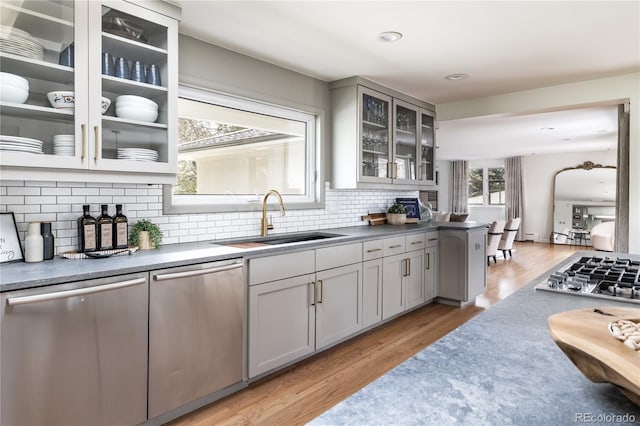 kitchen featuring a sink, decorative backsplash, gray cabinetry, and stainless steel appliances