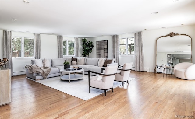 living area with a baseboard heating unit, plenty of natural light, baseboard heating, and light wood-style floors