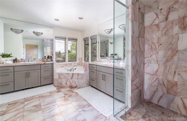 bathroom with a garden tub, two vanities, a sink, a walk in shower, and marble finish floor