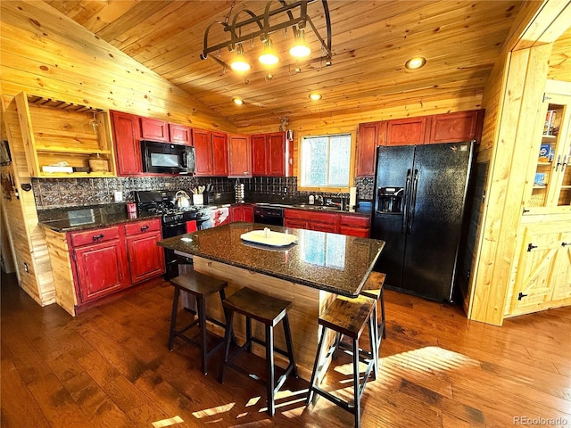 kitchen with wooden ceiling, vaulted ceiling, a kitchen breakfast bar, a kitchen island, and black appliances