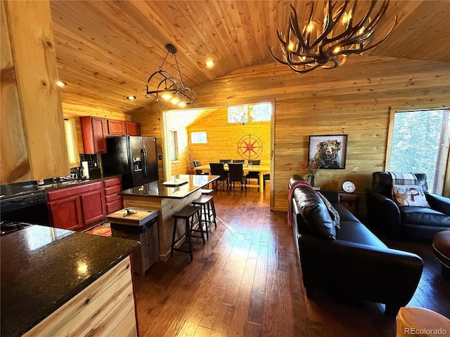 kitchen featuring vaulted ceiling, a center island, wood walls, black appliances, and wooden ceiling