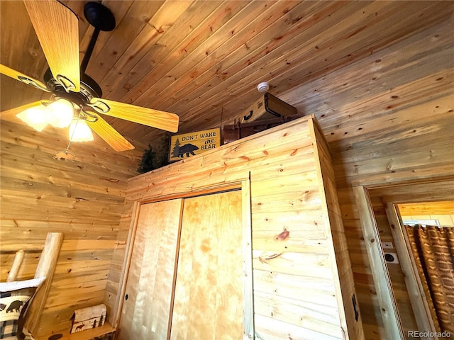 interior space featuring wood ceiling, ceiling fan, wooden walls, and a closet