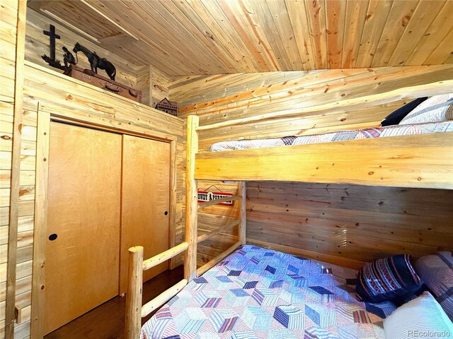 unfurnished bedroom with lofted ceiling, a closet, wooden ceiling, and wooden walls