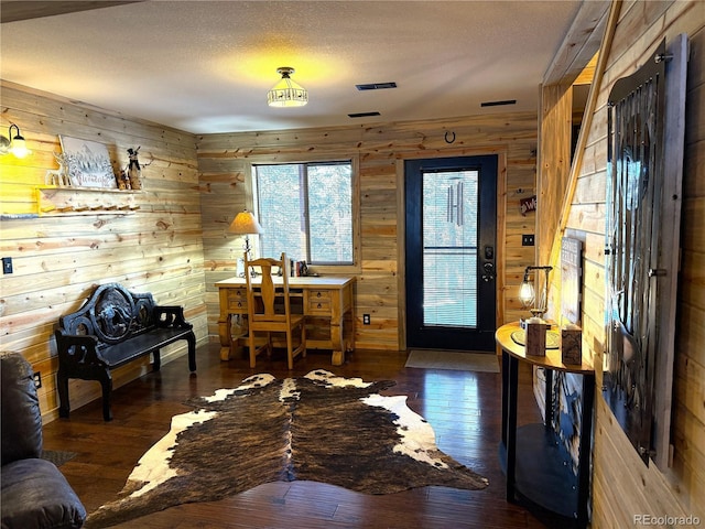 home office with dark hardwood / wood-style flooring, wood walls, and a textured ceiling