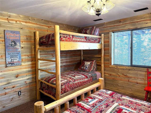 bedroom with a textured ceiling, a notable chandelier, and wood walls