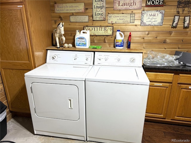 laundry room featuring wood walls and separate washer and dryer