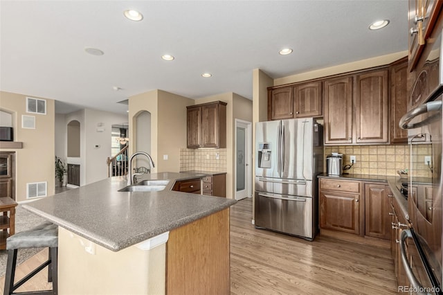 7852 Solstice Way, Castle Rock, CO 80108 - kitchen with stainless steel fridge, a sink, arched walkways, dark countertops, and light wood-style floors
