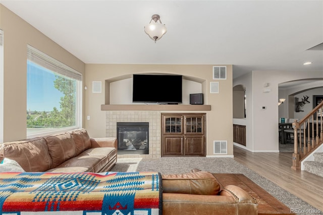 7852 Solstice Way, Castle Rock, CO 80108 - living room with arched walkways, wood finished floors, a tile fireplace, stairs, and baseboards