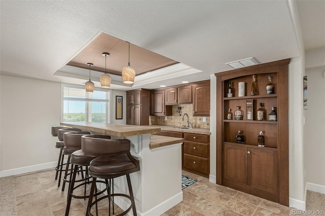 7852 Solstice Way, Castle Rock, CO 80108 - kitchen featuring a sink, a tray ceiling, a breakfast bar, baseboards, and light countertops