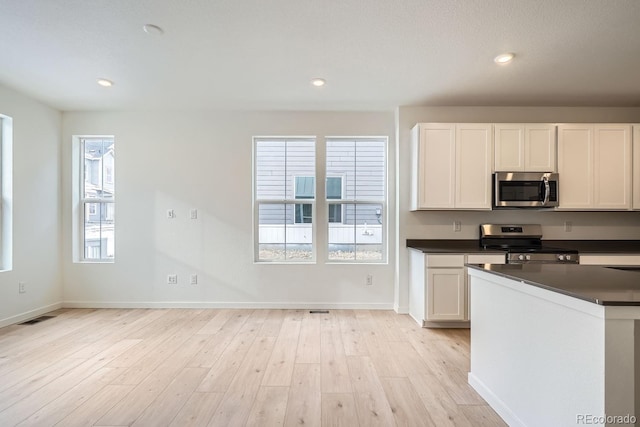 14556 W 91st Ave Unit D, Arvada, CO 80005 - kitchen with appliances with stainless steel finishes, dark countertops, light wood-style flooring, white cabinets, and recessed lighting
