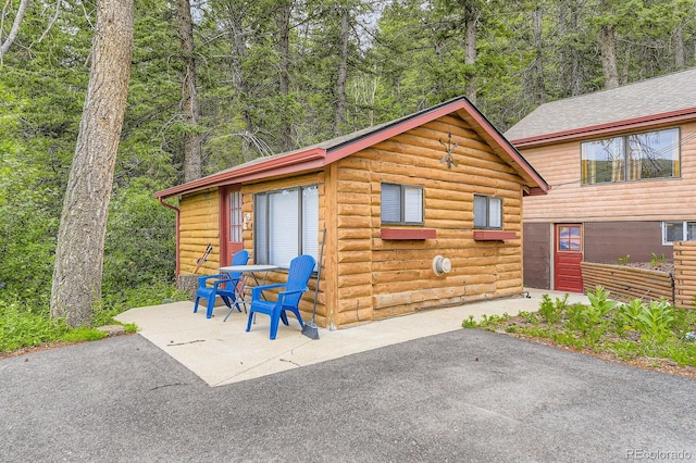 8758 S Murphy Gulch Rd, Littleton, CO 80127 - view of front of home featuring a patio area, faux log siding, and a wooded view