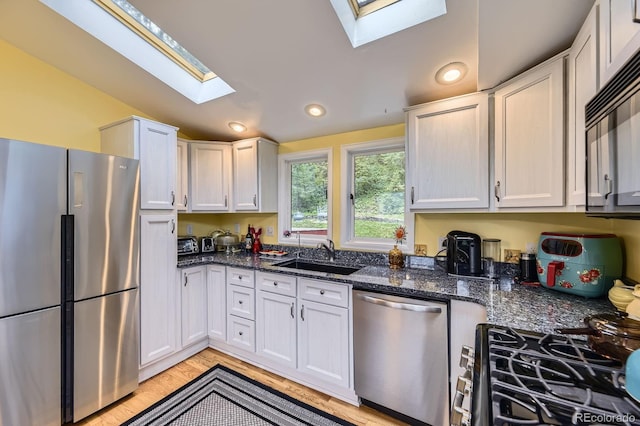 8758 S Murphy Gulch Rd, Littleton, CO 80127 - kitchen with appliances with stainless steel finishes, a skylight, dark stone counters, white cabinets, and recessed lighting
