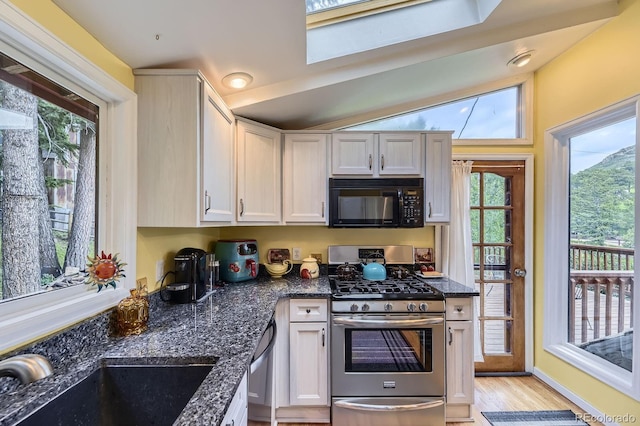 8758 S Murphy Gulch Rd, Littleton, CO 80127 - kitchen with stainless steel gas stove, black microwave, dishwasher, light wood finished floors, and dark stone countertops