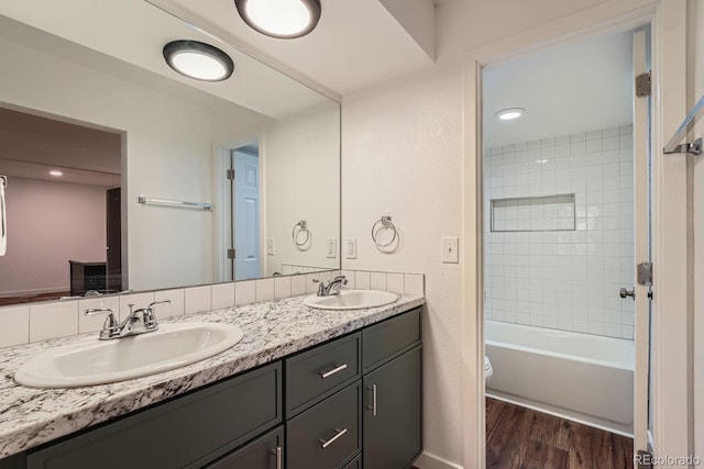 full bathroom featuring toilet, vanity, tiled shower / bath combo, and hardwood / wood-style flooring