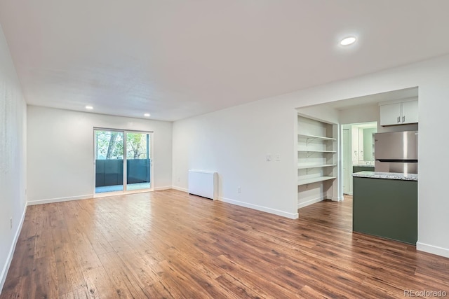 unfurnished living room featuring recessed lighting, baseboards, and wood finished floors