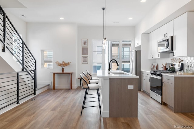5227 N Eliot St, Denver, CO 80221 - kitchen with stainless steel appliances, healthy amount of natural light, a kitchen breakfast bar, light wood finished floors, and recessed lighting
