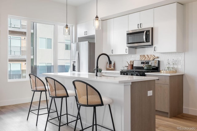 5227 N Eliot St, Denver, CO 80221 - kitchen with appliances with stainless steel finishes, light wood finished floors, a breakfast bar, decorative backsplash, and light countertops