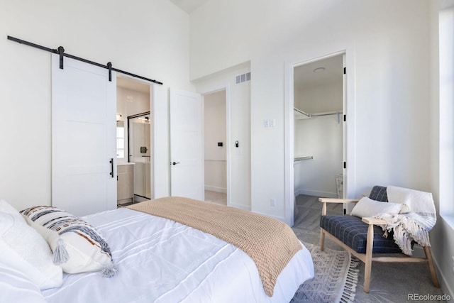 5227 N Eliot St, Denver, CO 80221 - bedroom with a barn door, carpet floors, a high ceiling, ensuite bathroom, and a closet