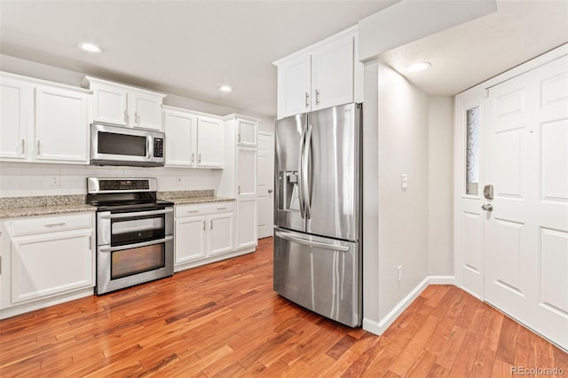 1461 S Danube Way Unit 104, Aurora, CO 80017 - kitchen featuring white cabinets, appliances with stainless steel finishes, light wood finished floors, baseboards, and backsplash