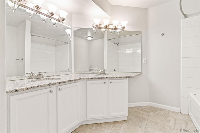 1461 S Danube Way Unit 104, Aurora, CO 80017 - bathroom featuring double vanity, baseboards, a notable chandelier, and a sink