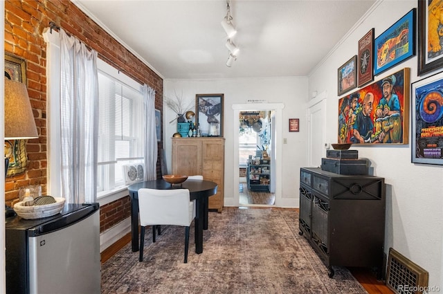 office area featuring hardwood / wood-style flooring, crown molding, track lighting, and brick wall