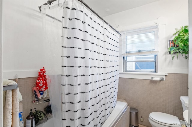 bathroom with tile walls, toilet, and shower / tub combo