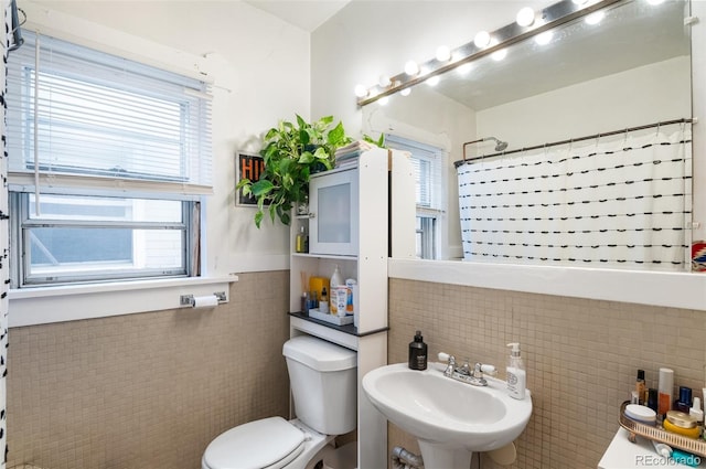 bathroom with sink, tile walls, toilet, and curtained shower