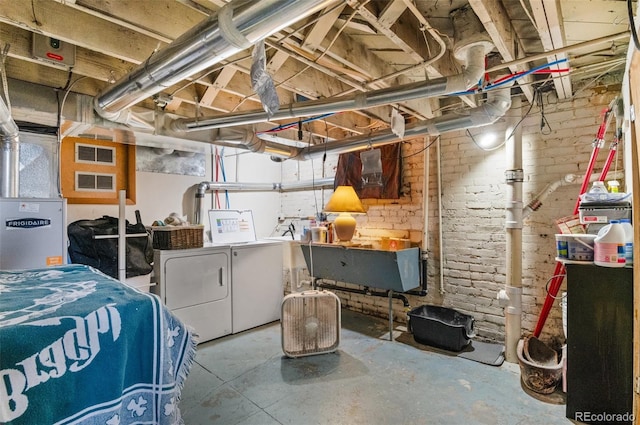 basement featuring brick wall, heating unit, washing machine and dryer, and a wealth of natural light