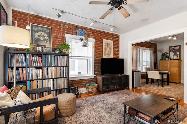 living room with ceiling fan, a textured ceiling, brick wall, and hardwood / wood-style flooring