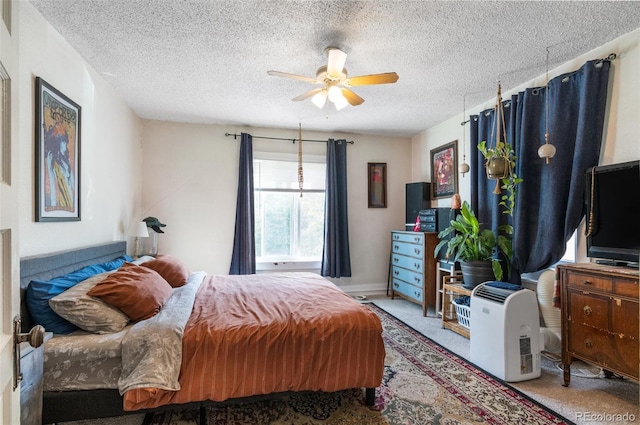 carpeted bedroom featuring ceiling fan and a textured ceiling