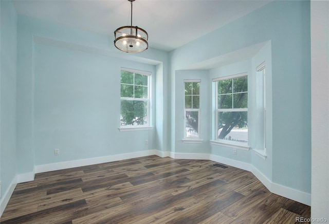 empty room with dark hardwood / wood-style flooring and a chandelier