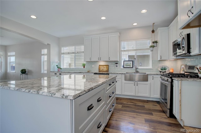 kitchen with white cabinets, appliances with stainless steel finishes, dark hardwood / wood-style flooring, and sink