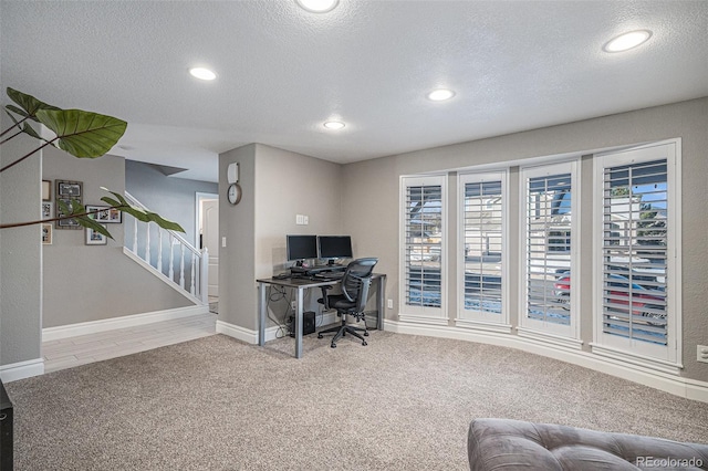 carpeted office with a textured ceiling and a wealth of natural light