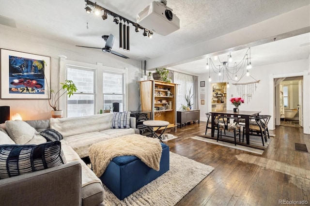 living room with ceiling fan with notable chandelier, dark hardwood / wood-style flooring, and a textured ceiling