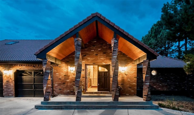 view of front of home featuring a garage, a tiled roof, and brick siding