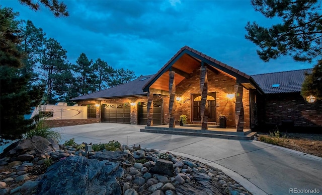 view of front of home with concrete driveway, fence, a garage, stone siding, and a tiled roof