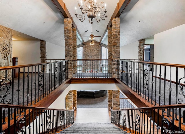 corridor featuring decorative columns, wood-type flooring, lofted ceiling, and a chandelier