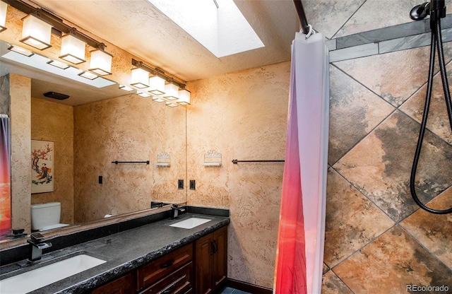 bathroom with vanity, toilet, and a skylight