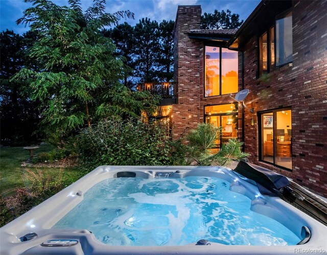 pool at dusk with a hot tub