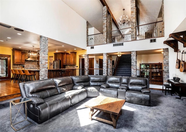 carpeted living room featuring ornate columns and a chandelier