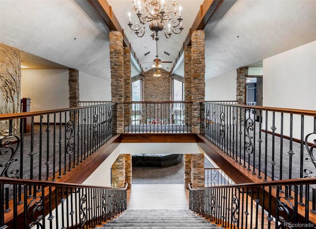 hall featuring high vaulted ceiling, a chandelier, decorative columns, and wood finished floors