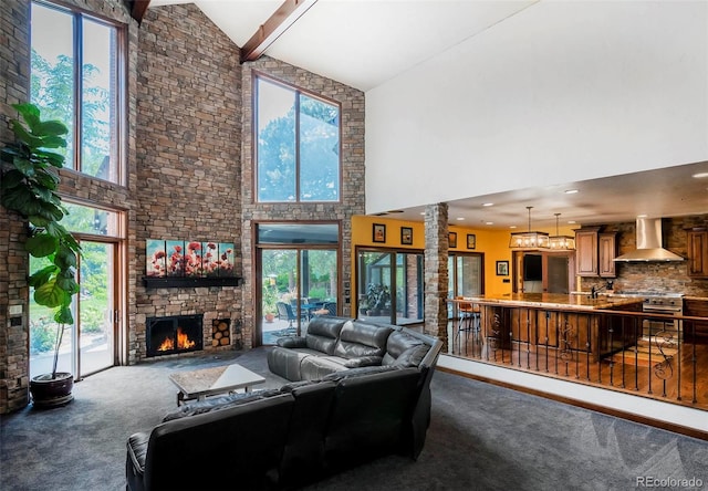 living room featuring beam ceiling, high vaulted ceiling, ornate columns, a fireplace, and dark colored carpet