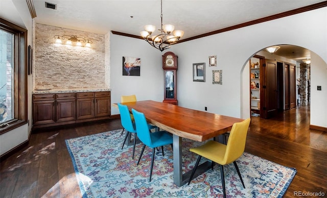 dining area featuring an inviting chandelier, visible vents, crown molding, dark wood-type flooring, and arched walkways