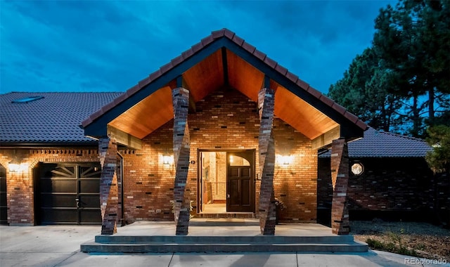 exterior space featuring a tile roof, concrete driveway, a garage, and brick siding